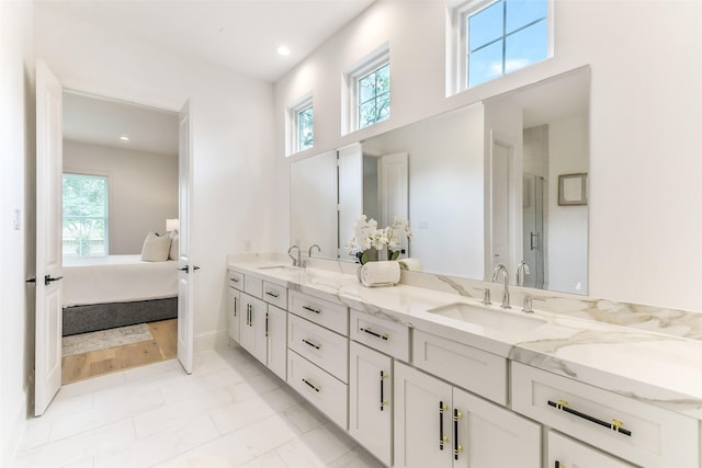 ensuite bathroom featuring connected bathroom, double vanity, a healthy amount of sunlight, and a sink