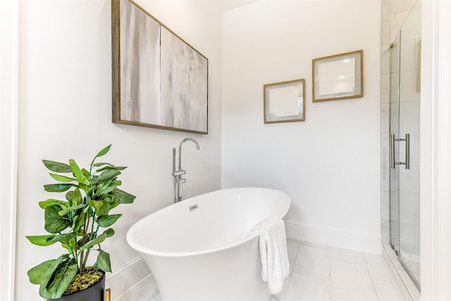 bathroom featuring baseboards, a freestanding bath, a shower stall, and marble finish floor