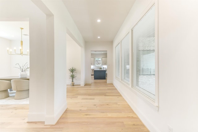 hall featuring recessed lighting, baseboards, a chandelier, and light wood finished floors