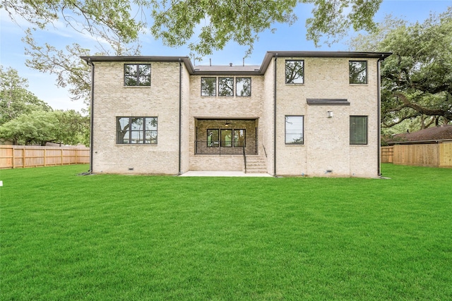 back of house with a lawn, fence, and brick siding