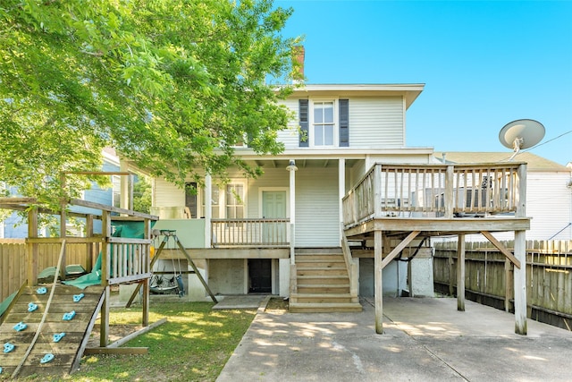 rear view of property featuring fence, stairs, and a playground