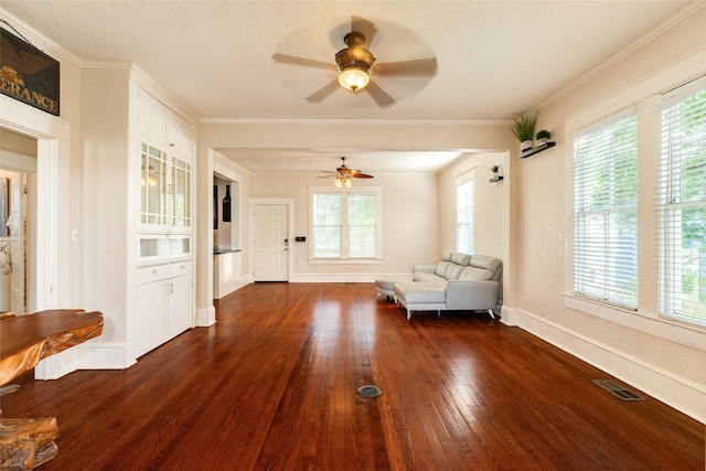 unfurnished living room featuring visible vents, crown molding, baseboards, dark wood-style floors, and a ceiling fan