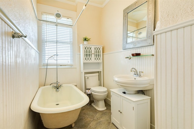 full bath with a freestanding bath, a sink, toilet, a wainscoted wall, and ornamental molding