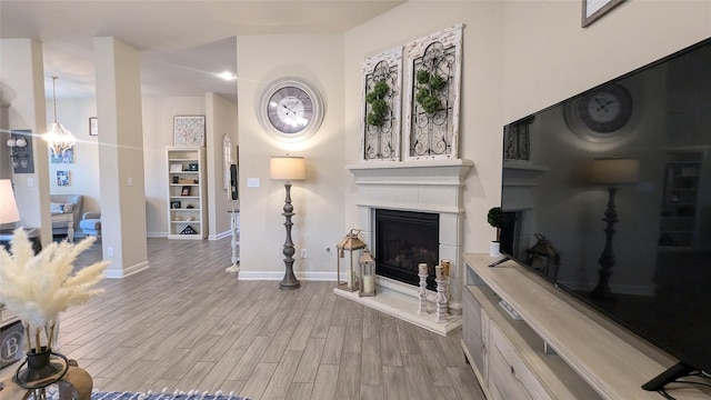 12813 Narrow Cove Dr, Texas City, TX 77568 - unfurnished living room with a glass covered fireplace, baseboards, wood finished floors, and a chandelier