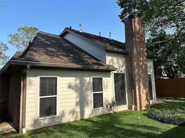 back of property with fence, a shingled roof, a lawn, and a chimney