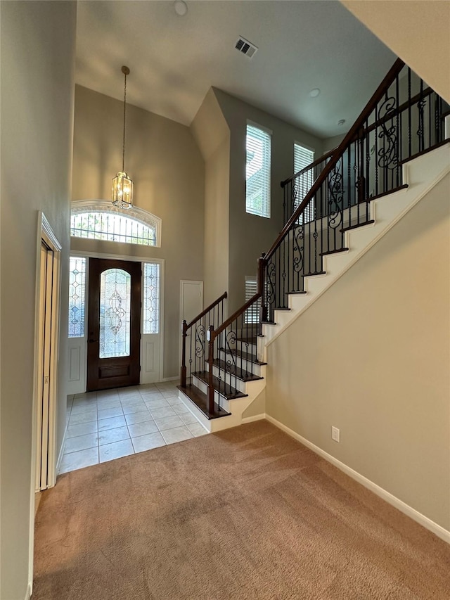 tiled entrance foyer with visible vents, baseboards, a high ceiling, stairway, and carpet flooring