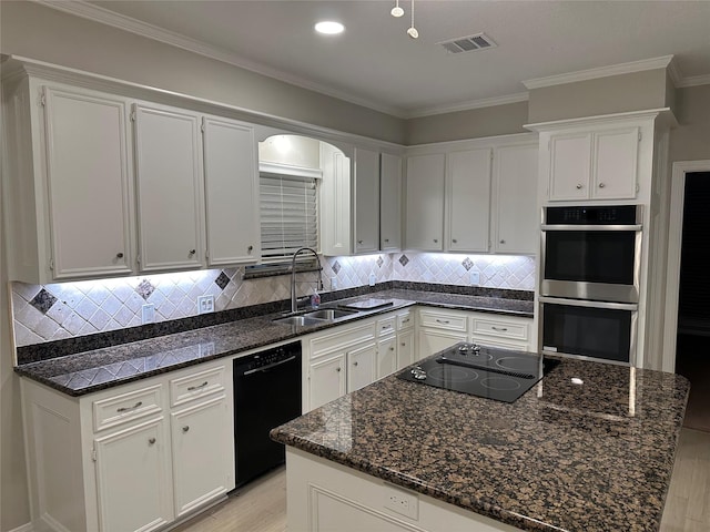 kitchen with a sink, black appliances, light wood finished floors, ornamental molding, and white cabinetry