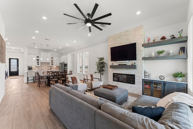 living room with a fireplace, a ceiling fan, light wood-type flooring, and a wealth of natural light