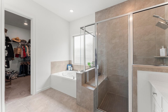 full bathroom with tile patterned flooring, a bath, a spacious closet, and a shower stall