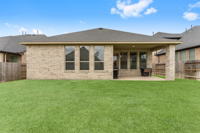 back of house with a fenced backyard, a patio, a yard, and brick siding