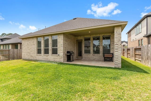 rear view of property featuring brick siding, a fenced backyard, and a patio