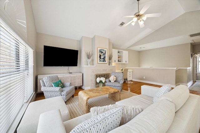 living area with baseboards, visible vents, wood finished floors, and lofted ceiling