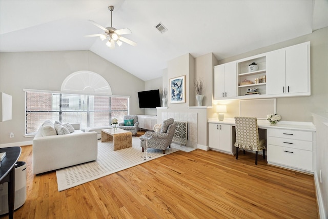 living room with visible vents, high vaulted ceiling, light wood-type flooring, built in desk, and a ceiling fan