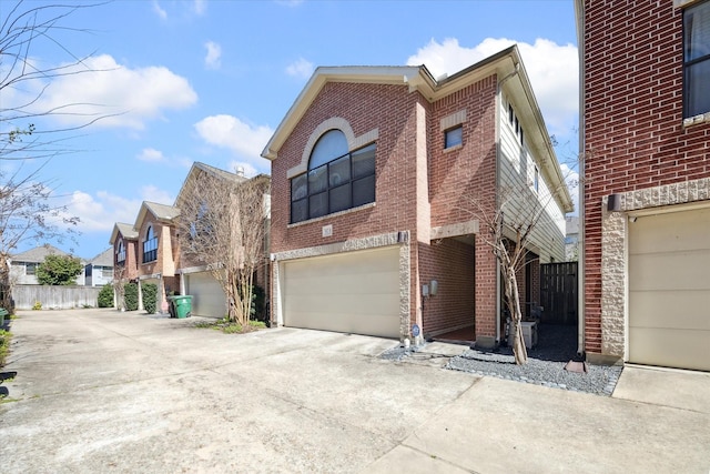 view of front of home featuring brick siding, driveway, fence, and a garage