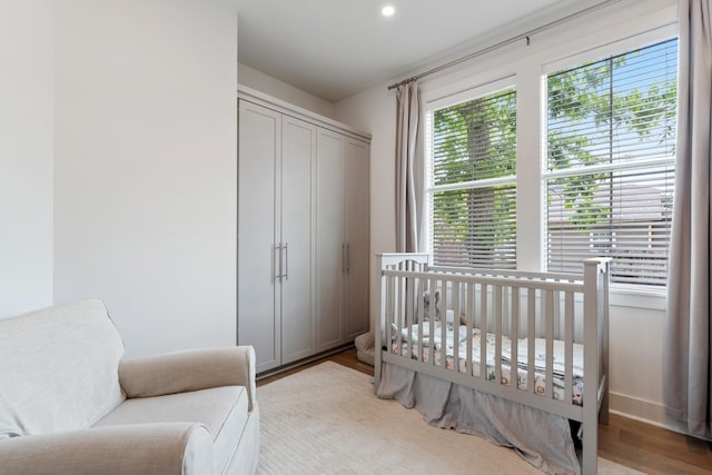 bedroom featuring a closet, a crib, and wood finished floors
