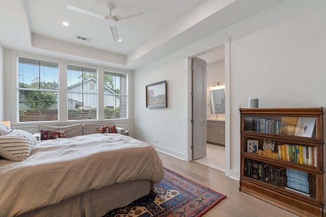 bedroom featuring light wood-style flooring, a ceiling fan, baseboards, ensuite bathroom, and visible vents