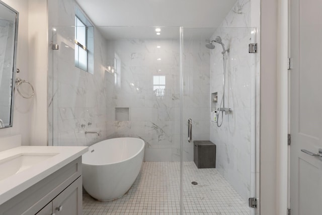 full bath featuring a freestanding bath, tile patterned flooring, vanity, a marble finish shower, and tile walls
