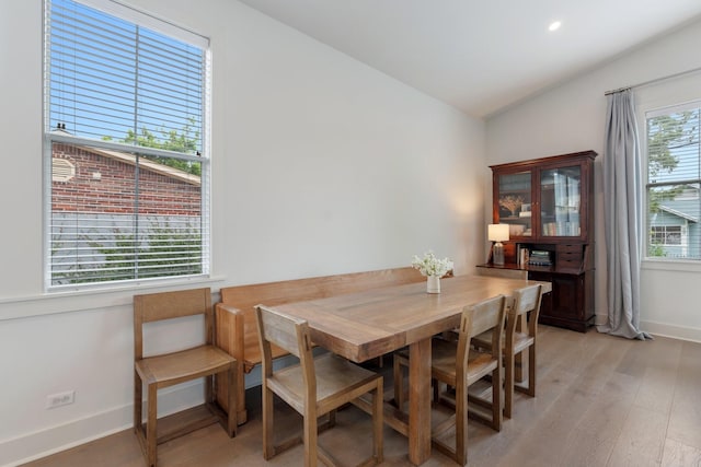 dining space with baseboards, light wood-type flooring, and lofted ceiling