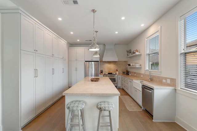 kitchen featuring plenty of natural light, visible vents, appliances with stainless steel finishes, a sink, and custom range hood
