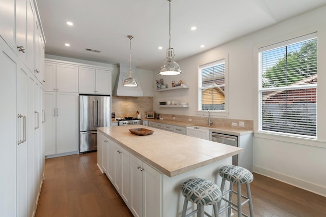 kitchen with decorative backsplash, wood finished floors, a sink, recessed lighting, and high end fridge