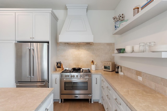 kitchen featuring white cabinets, premium appliances, custom exhaust hood, and light countertops