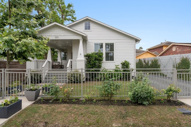 view of front of house with a porch, a garden, fence private yard, and a front lawn