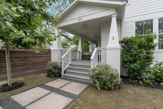 entrance to property with covered porch and fence