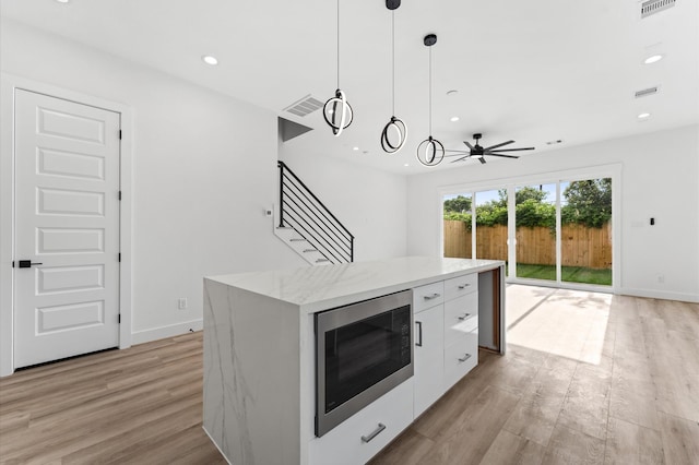 kitchen featuring visible vents, modern cabinets, stainless steel microwave, light wood finished floors, and white cabinetry