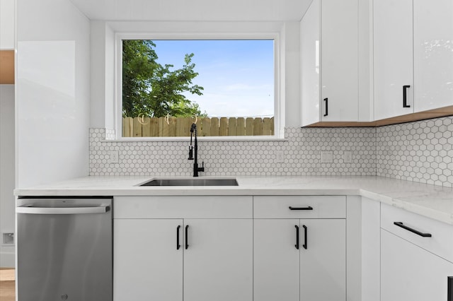 kitchen with light stone counters, a sink, dishwasher, white cabinetry, and tasteful backsplash