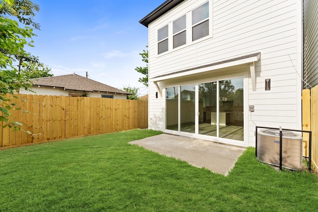 rear view of house with a lawn, central AC unit, fence, and a patio