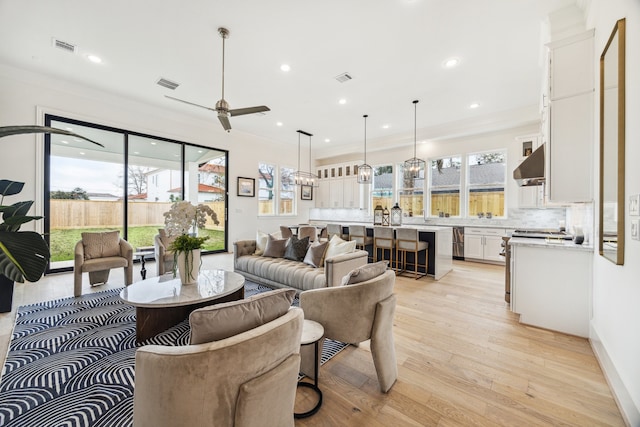 living room featuring recessed lighting, visible vents, ornamental molding, and light wood-style floors