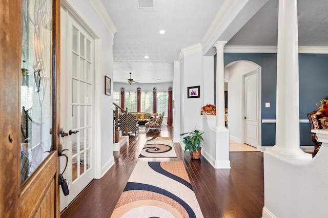 foyer with crown molding, arched walkways, baseboards, ornate columns, and hardwood / wood-style floors