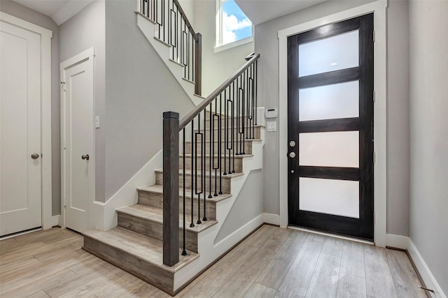 entryway with stairway, baseboards, and wood finished floors