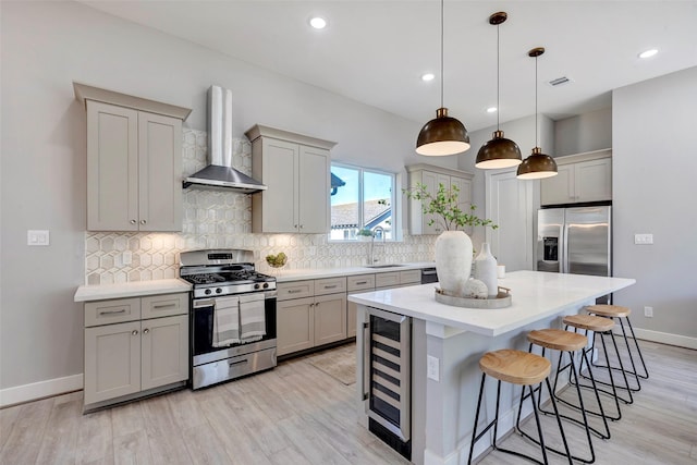 kitchen featuring beverage cooler, wall chimney exhaust hood, gray cabinets, a sink, and stainless steel appliances