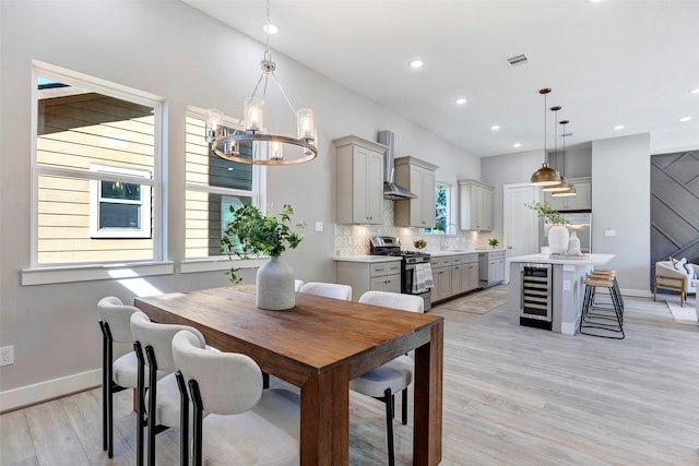 dining space with baseboards, light wood finished floors, beverage cooler, a chandelier, and recessed lighting