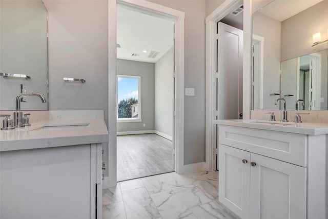 full bath featuring visible vents, two vanities, a sink, baseboards, and marble finish floor
