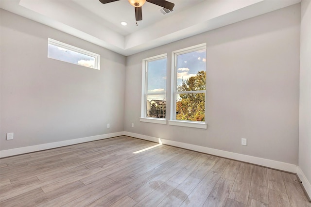 spare room with wood finished floors, baseboards, ceiling fan, recessed lighting, and a tray ceiling