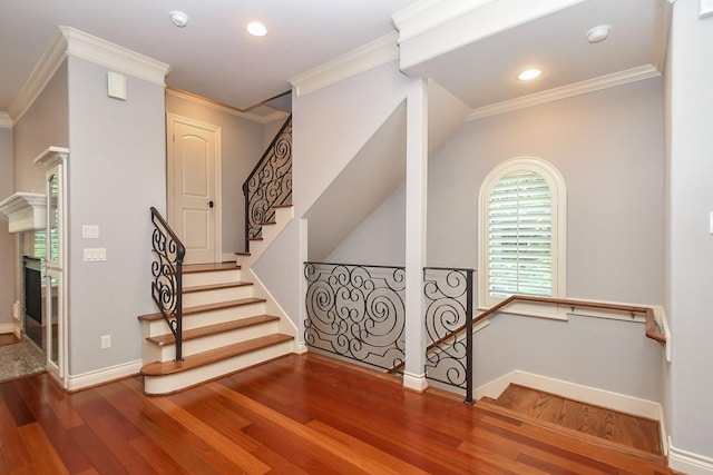 staircase with baseboards, crown molding, wood finished floors, and a fireplace