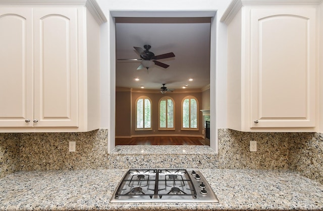 kitchen featuring ornamental molding, white cabinetry, a ceiling fan, backsplash, and stainless steel gas stovetop