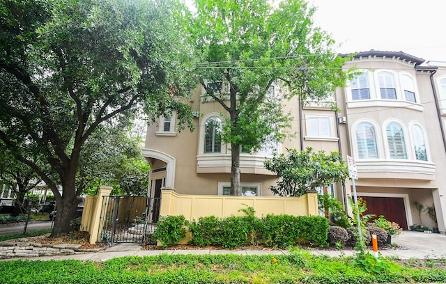 view of front facade featuring an attached garage, fence, driveway, and stucco siding