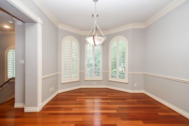 unfurnished dining area with baseboards, visible vents, ornamental molding, and wood finished floors