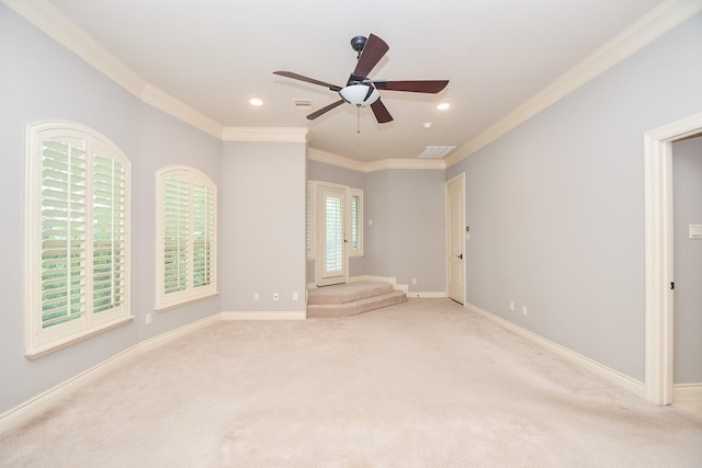 spare room featuring crown molding, ceiling fan, visible vents, and light colored carpet