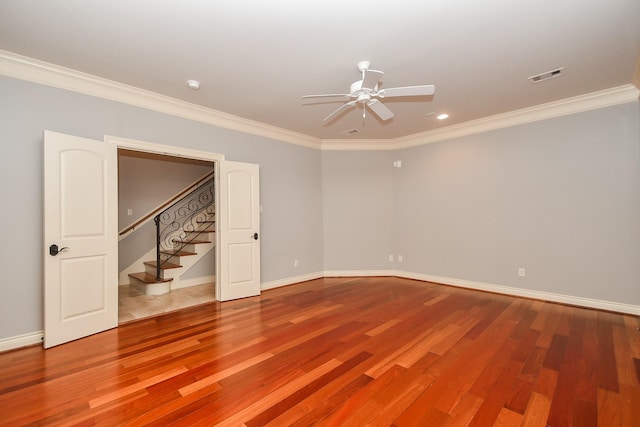 empty room with ceiling fan, visible vents, ornamental molding, and wood finished floors