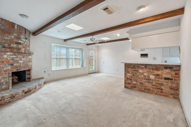 unfurnished living room featuring visible vents, carpet floors, a fireplace, beamed ceiling, and baseboards