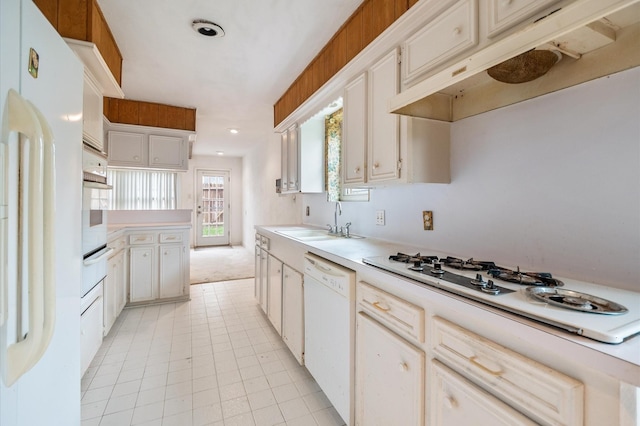 kitchen with a sink, light countertops, a warming drawer, under cabinet range hood, and white appliances