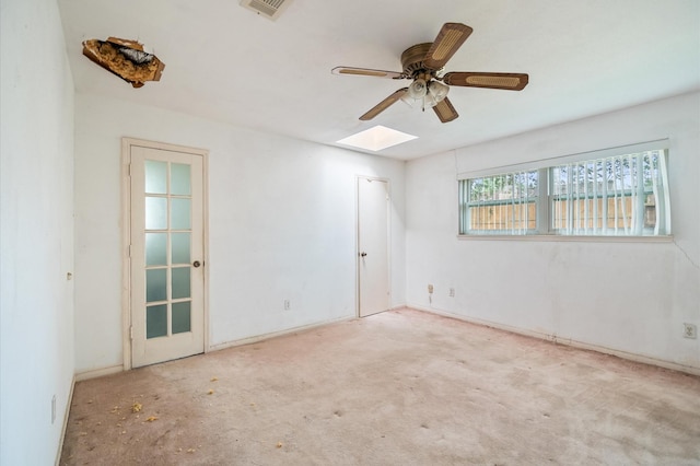 spare room with a skylight, a ceiling fan, and visible vents