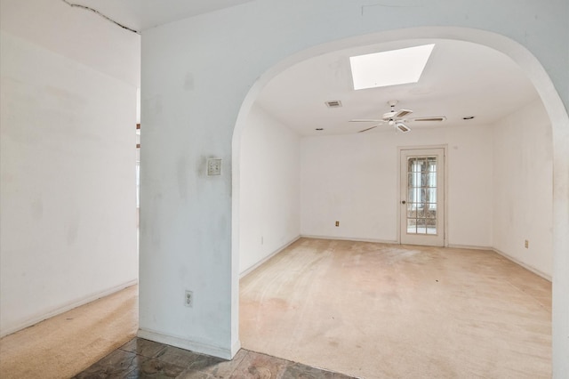 empty room with arched walkways, a ceiling fan, visible vents, and carpet