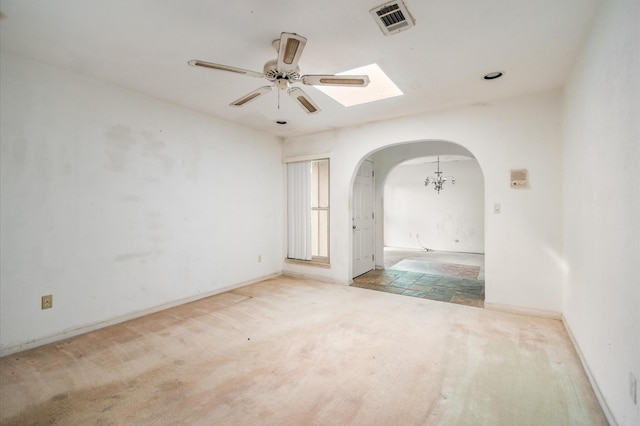 carpeted empty room with arched walkways, a ceiling fan, visible vents, and baseboards