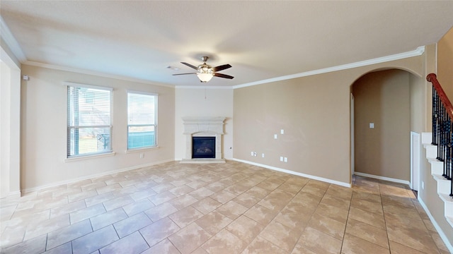 unfurnished living room featuring a ceiling fan, arched walkways, a glass covered fireplace, ornamental molding, and stairs