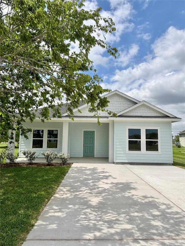 ranch-style house featuring concrete driveway and a front lawn